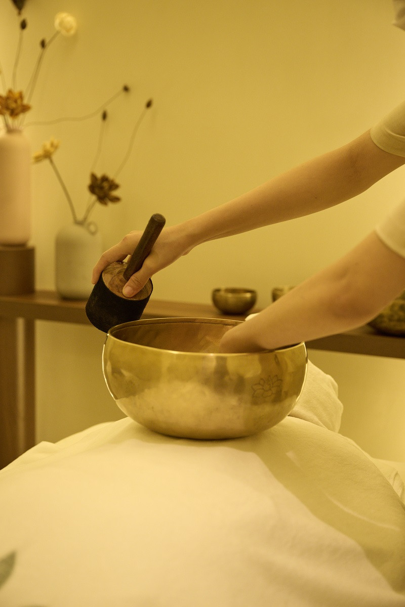 Một người đang thực hành trị liệu với chuông xoay Tây Tạng, tập trung vào việc tạo ra âm thanh chữa lành trong một không gian yên bình.