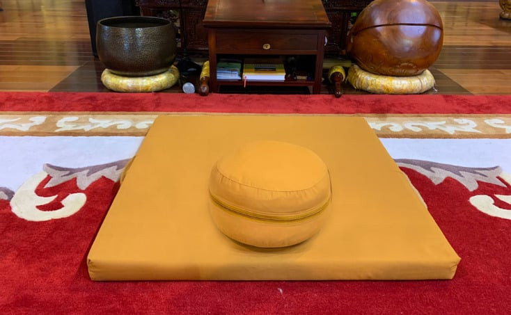Một vị thiền sư đang ngồi thiền trên bồ đoàn với tư thế kiết già, thể hiện sự định tâm và an lạc