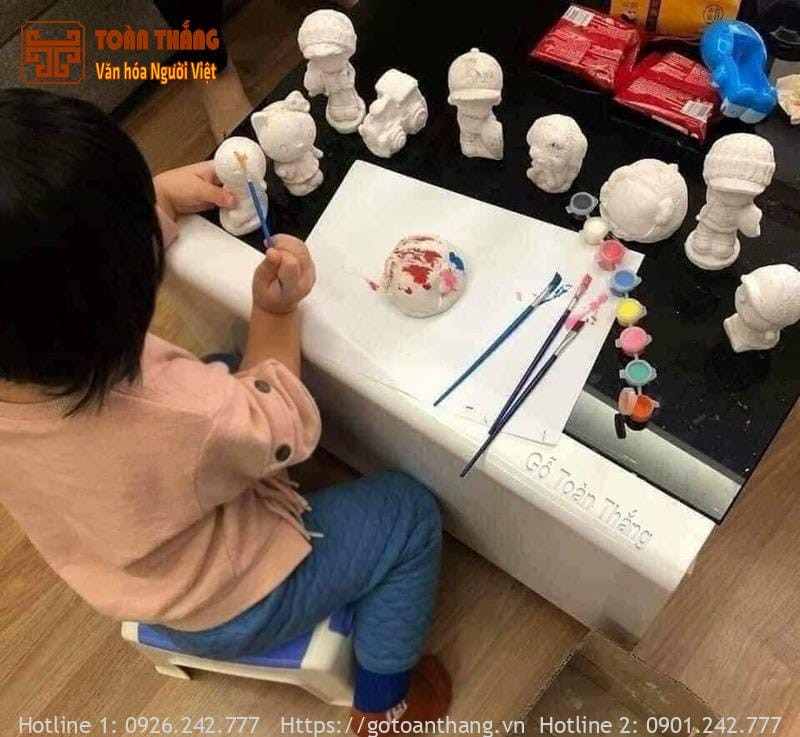 Người đang tỉ mỉ tô từng chi tiết nhỏ trên khuôn mặt và trang phục của tượng Thần Tài