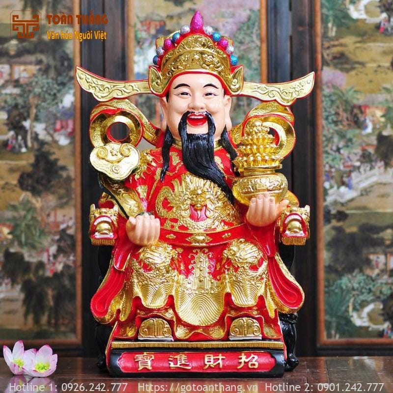 Tượng Thần Tài đã được tô màu hoàn thiện, đặt trên kệ sách cùng các vật phẩm trang trí khác, tạo không khí ấm cúng