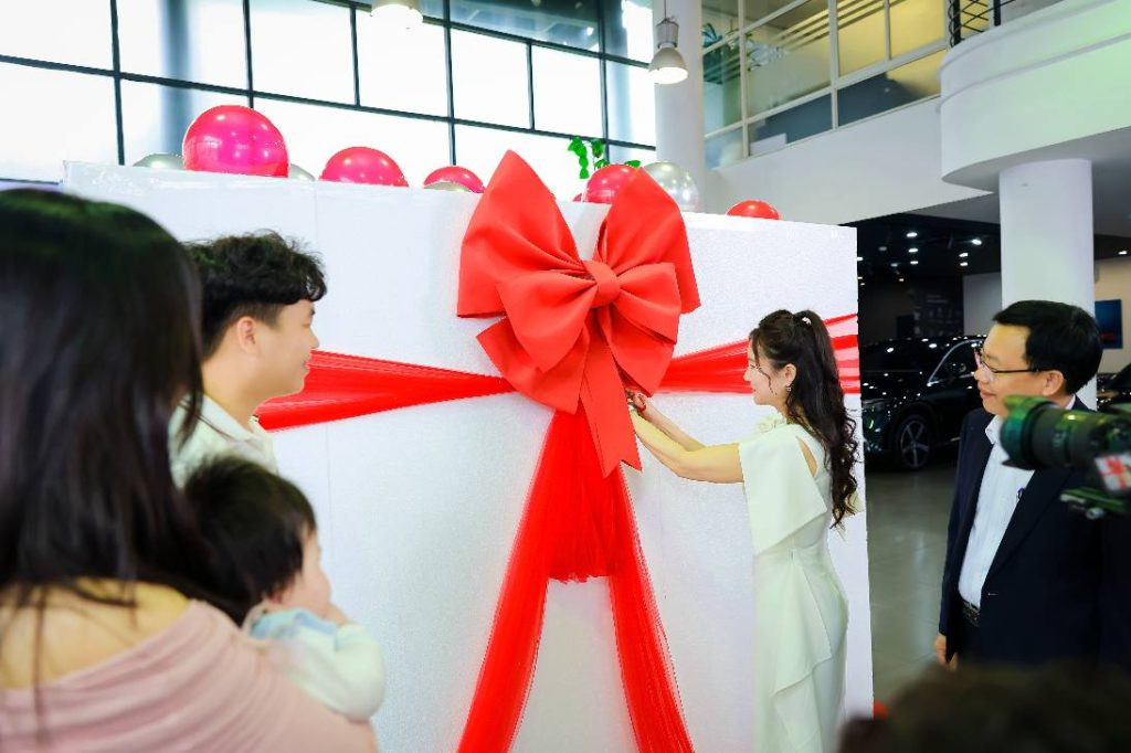 Xe ô tô sang trọng trong hộp quà kính trong suốt được trang trí bóng bay lộng lẫy, tạo điểm nhấn cho lễ bàn giao xe